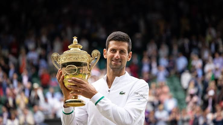 Roland-Garros VS Wimbledon : Novak Djokovic soulevant le trophée du tournoi Londonien.