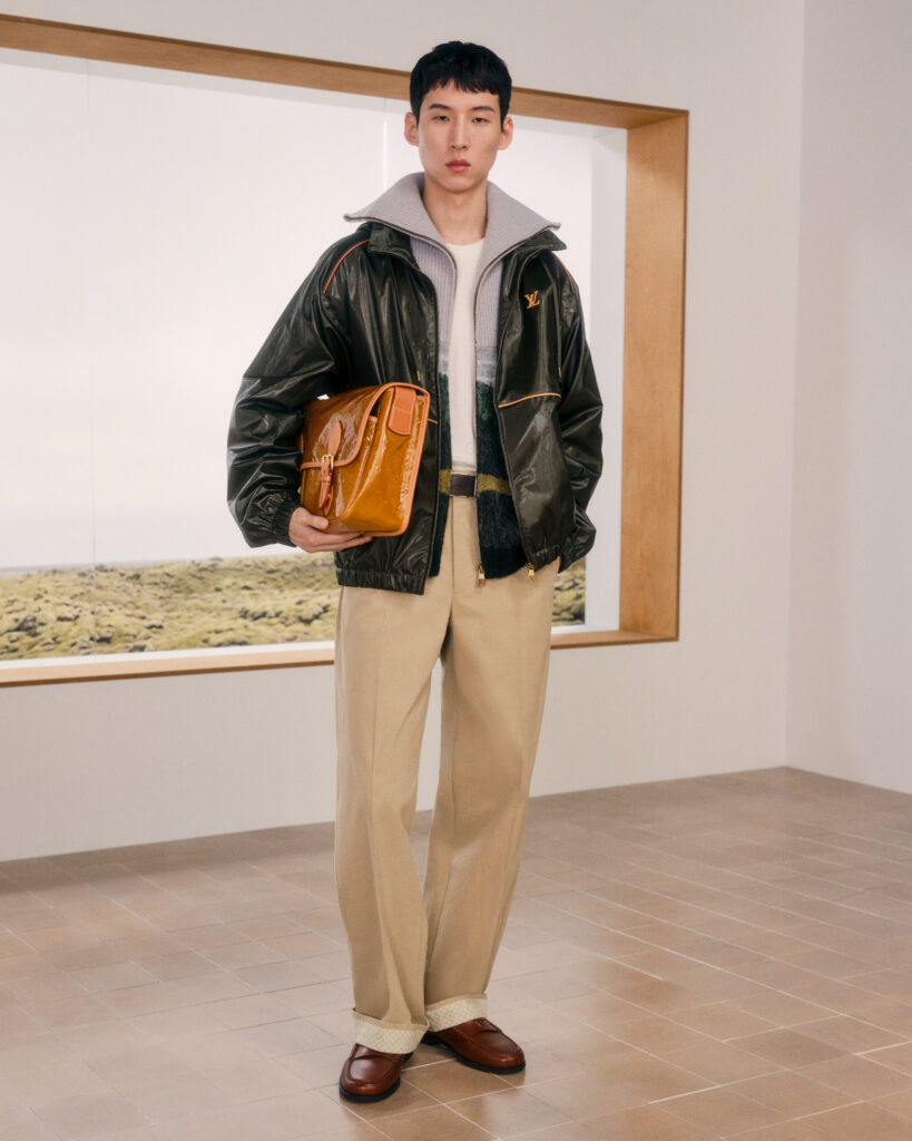 Look 5 Louis Vuitton Homme : blouson en denim brut, pull à motifs et sac Keepall en cuir vernis