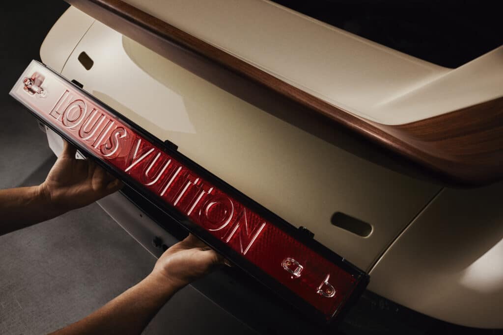 Feu arrière rouge illuminé portant l'inscription Louis Vuitton, tenu à la main près de la carrosserie ivoire, Singer x Louis Vuitton Interview