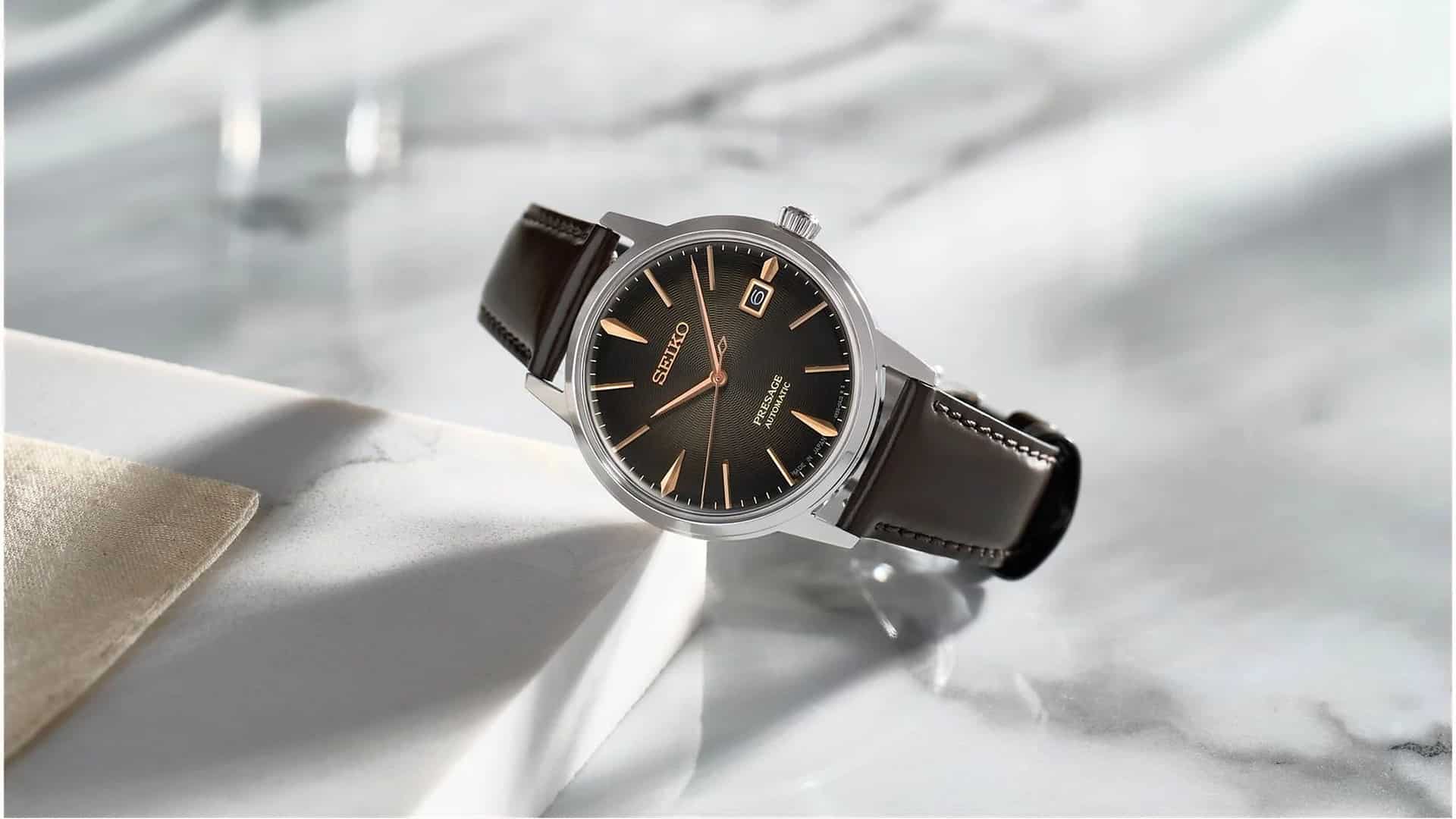 Montre Seiko Presage automatique à cadran noir texturé et aiguilles or rose, bracelet en cuir marron, posée sur un plan en marbre blanc