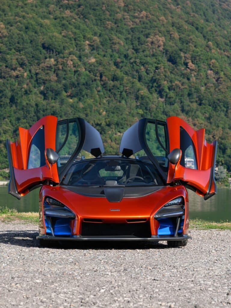 McLaren Senna Volcano Orange vue de face avec ses portes ouvertes au bord du lac