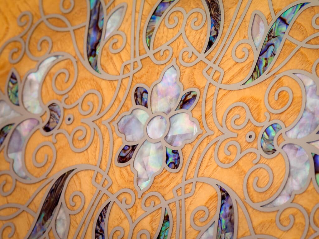 Gros plan sur les volutes et incrustations de nacre et d'ormeau de la marqueterie florale