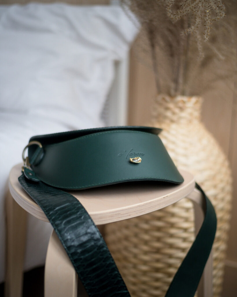 Accessoire vert en cuir avec coutures apparentes et éléments métalliques