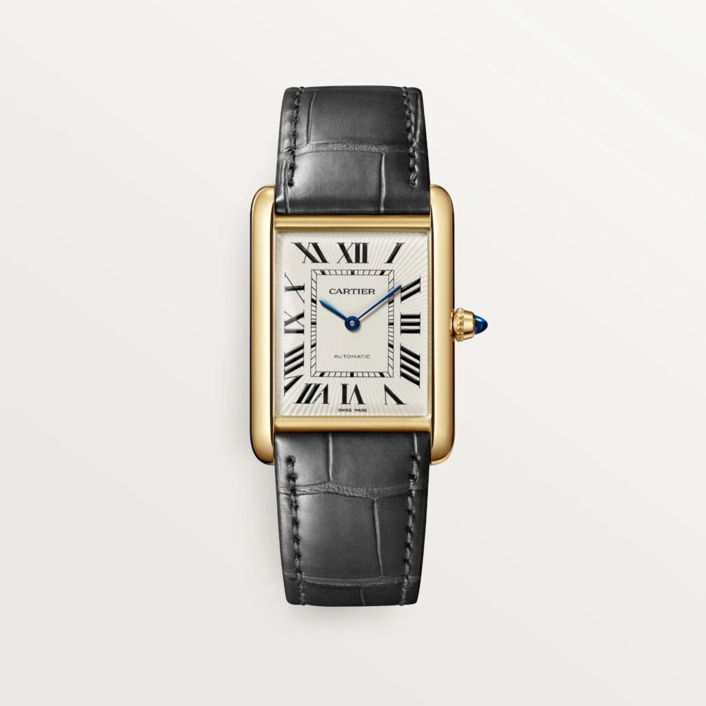 Cartier les plus désirables 2026 : Montre Tank Louis Cartier grand modèle automatique en or jaune sur cuir gris, vue de face