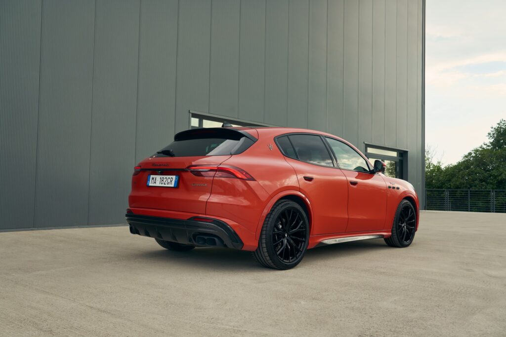 Maserati Grecale Trofeo orange vue de trois-quarts arrière devant un bâtiment industriel, diffuseur et jantes noires