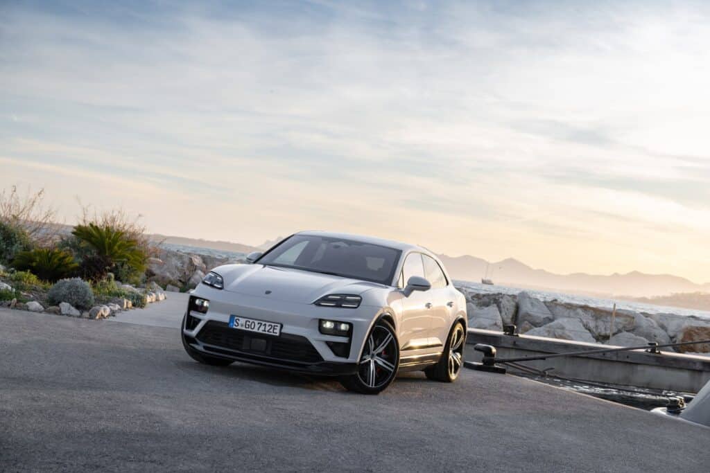 Les 10 SUV de luxe les plus sportifs en 2026 : Porsche Macan Turbo électrique gris Ice Grey vu de trois-quarts avant sur un quai en bord de mer