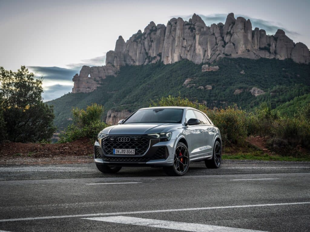 Les 10 SUV de luxe les plus sportifs en 2026 : Audi RS Q8 performance gris Satellite vu de trois-quarts avant sur une route devant un massif rocheux