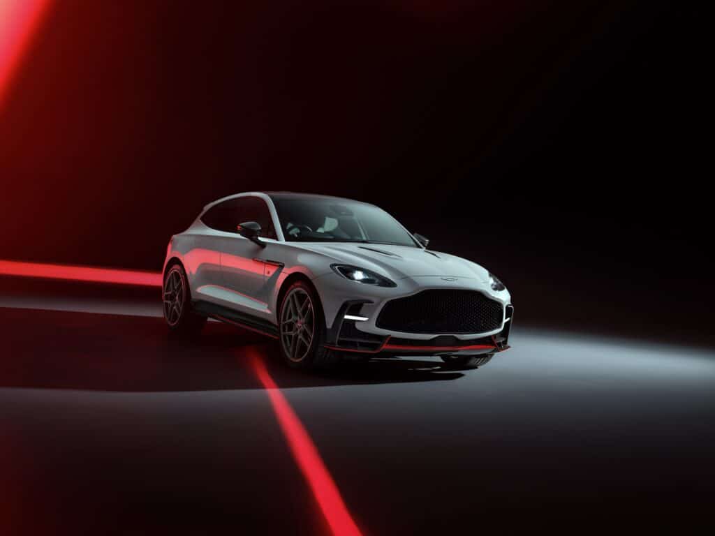 Les 10 SUV de luxe les plus sportifs en 2026 : Aston Martin DBX S blanche vue de trois-quarts avant sur fond sombre éclairé de rouge