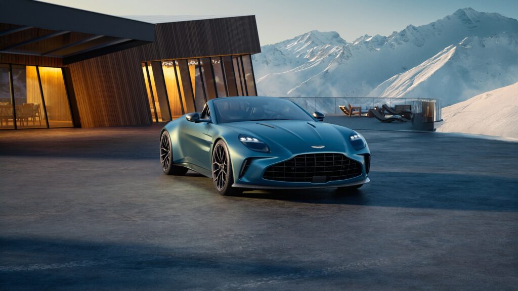 Les 10 Aston Martin les plus désirables en 2026 : Aston Martin Vantage Roadster bleu-vert décapotée, vue de trois-quarts avant devant un chalet de montagne