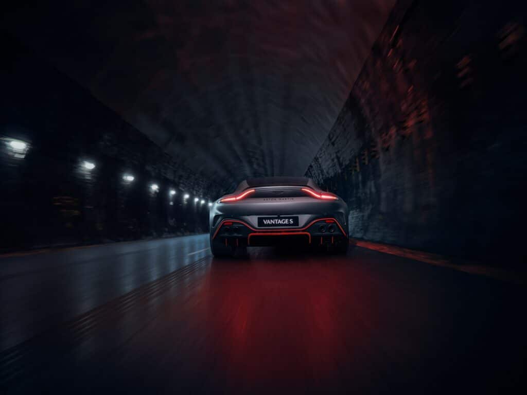 Aston Martin Vantage S vue de l'arrière dans un tunnel, feux allumés et logo Vantage S