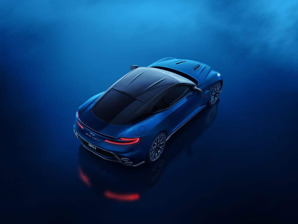 Aston Martin DB12 S bleue vue de trois-quarts arrière en plongée, feux allumés