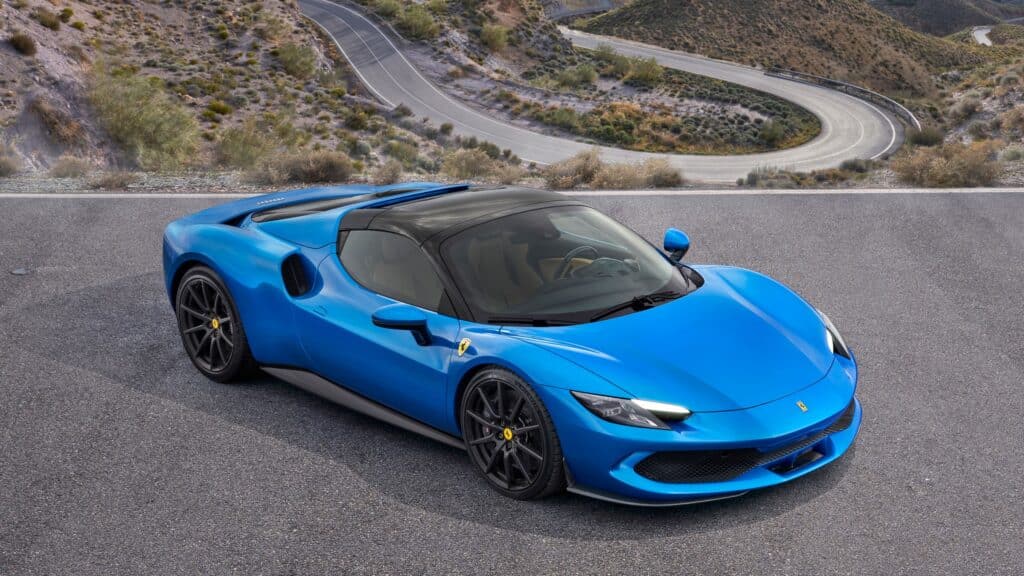 Les 10 Ferrari modernes les plus désirables en 2026 : Ferrari 296 GTS bleue toit rigide fermé, vue de trois-quarts avant en plongée sur une route de montagne