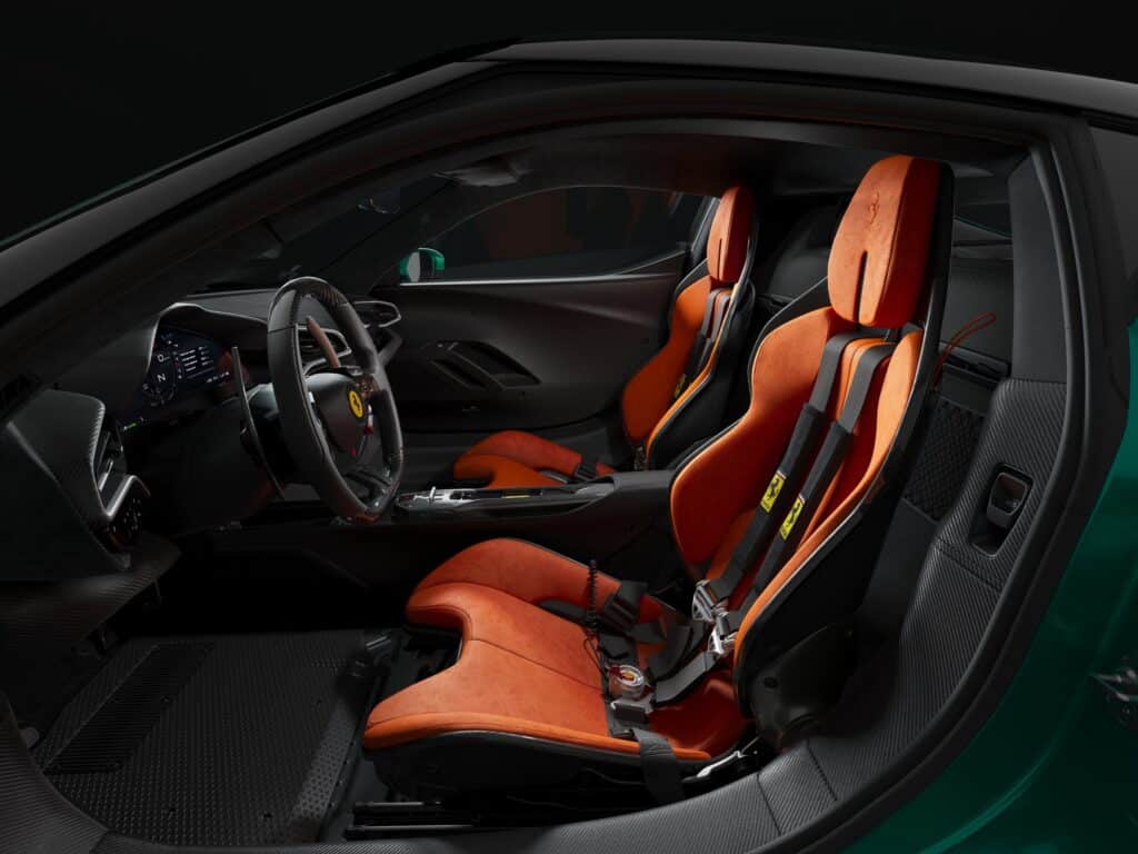 Habitacle de la Ferrari 296 Speciale, sièges baquets orange et harnais vus par la portière