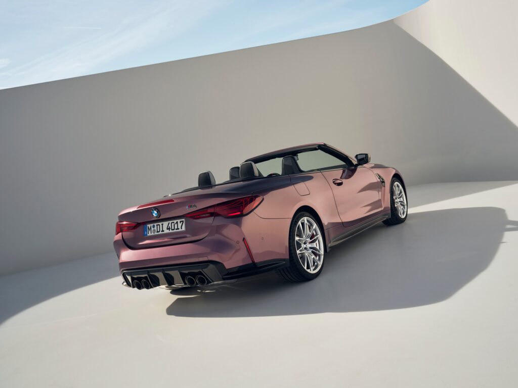 BMW M4 Competition Cabriolet M xDrive vieux rose décapotée dans un décor de studio, vue de trois-quarts arrière
