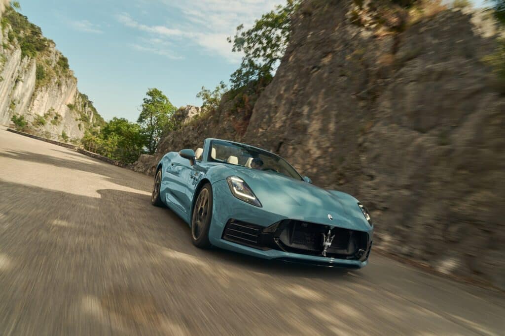 Les 10 cabriolets de luxe les plus désirables en 2026 :Maserati GranCabrio Folgore bleu clair décapotée en virage entre des falaises, vue de trois-quarts avant