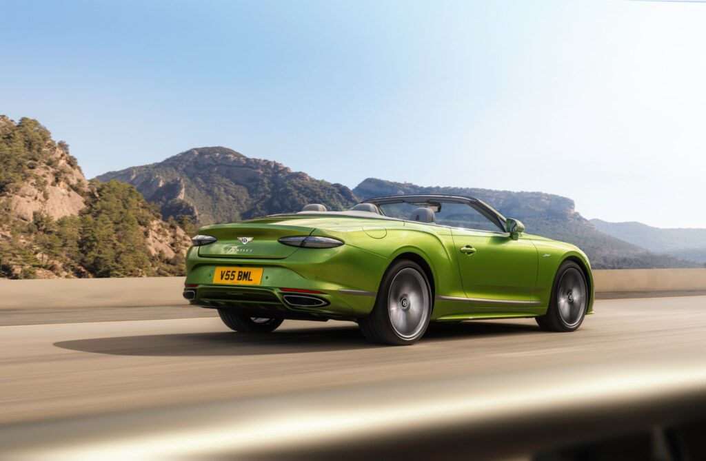 Bentley Continental GTC Speed verte décapotée en mouvement sur une route de montagne, vue de trois-quarts arrière